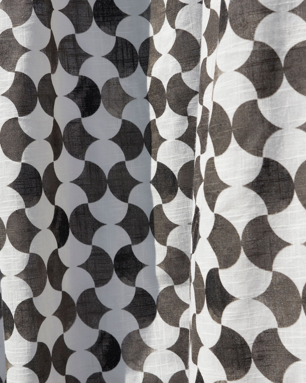 Close-up of Jamiti Shower Curtain fabric with a black and white scallop print and slub texture.