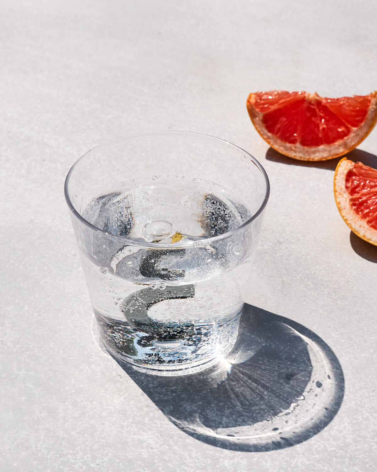 Clear Alphabet glass with a 3D letter C at the base, filled with sparkling water.