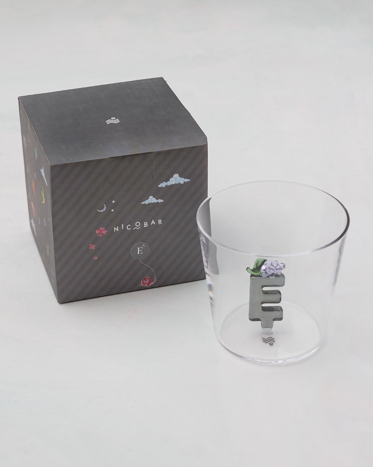 Clear Alphabet glass with a 3D letter E beside a charcoal Nicobar gift box.