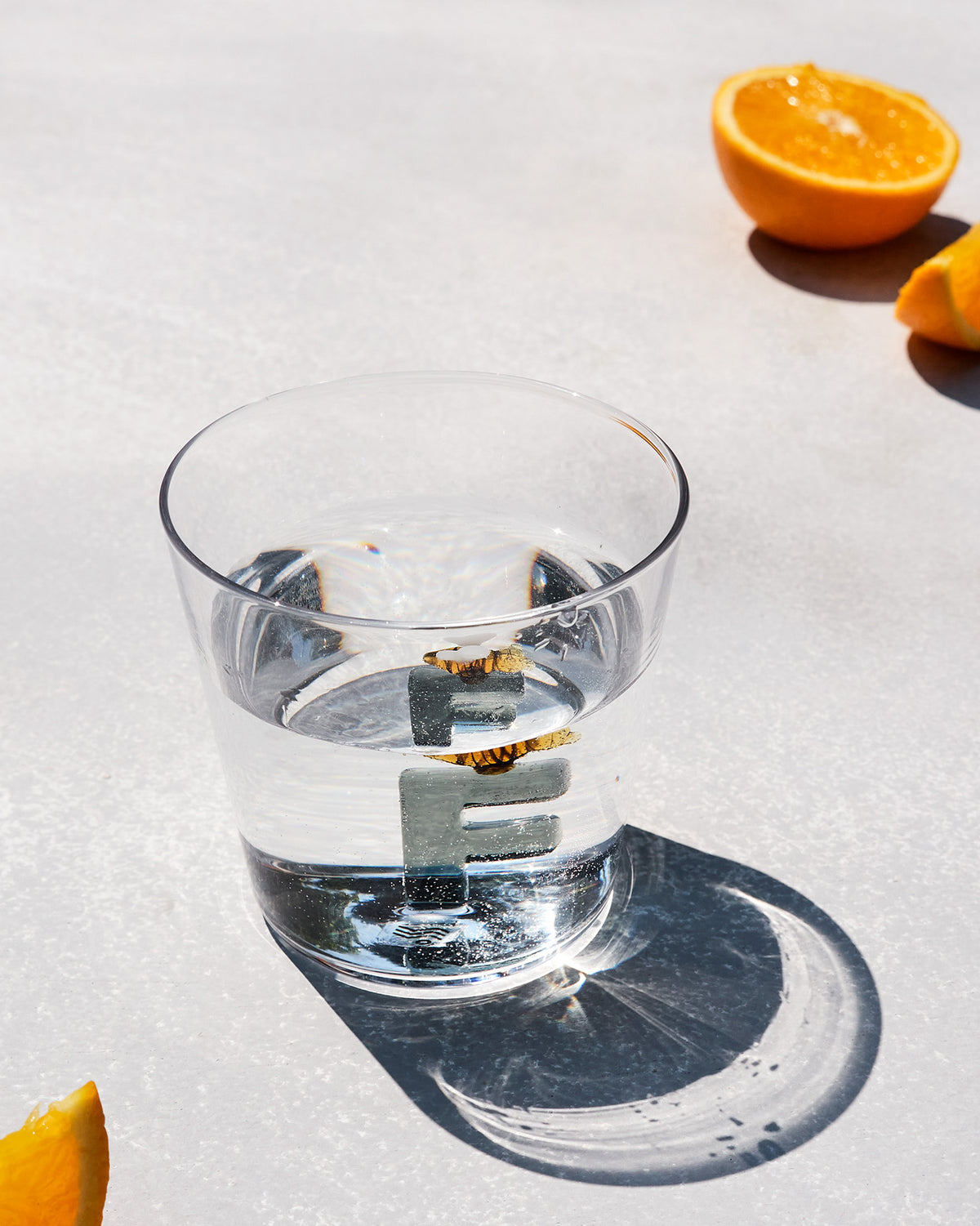 Clear Alphabet glass with a 3D letter F at the base, filled with water.