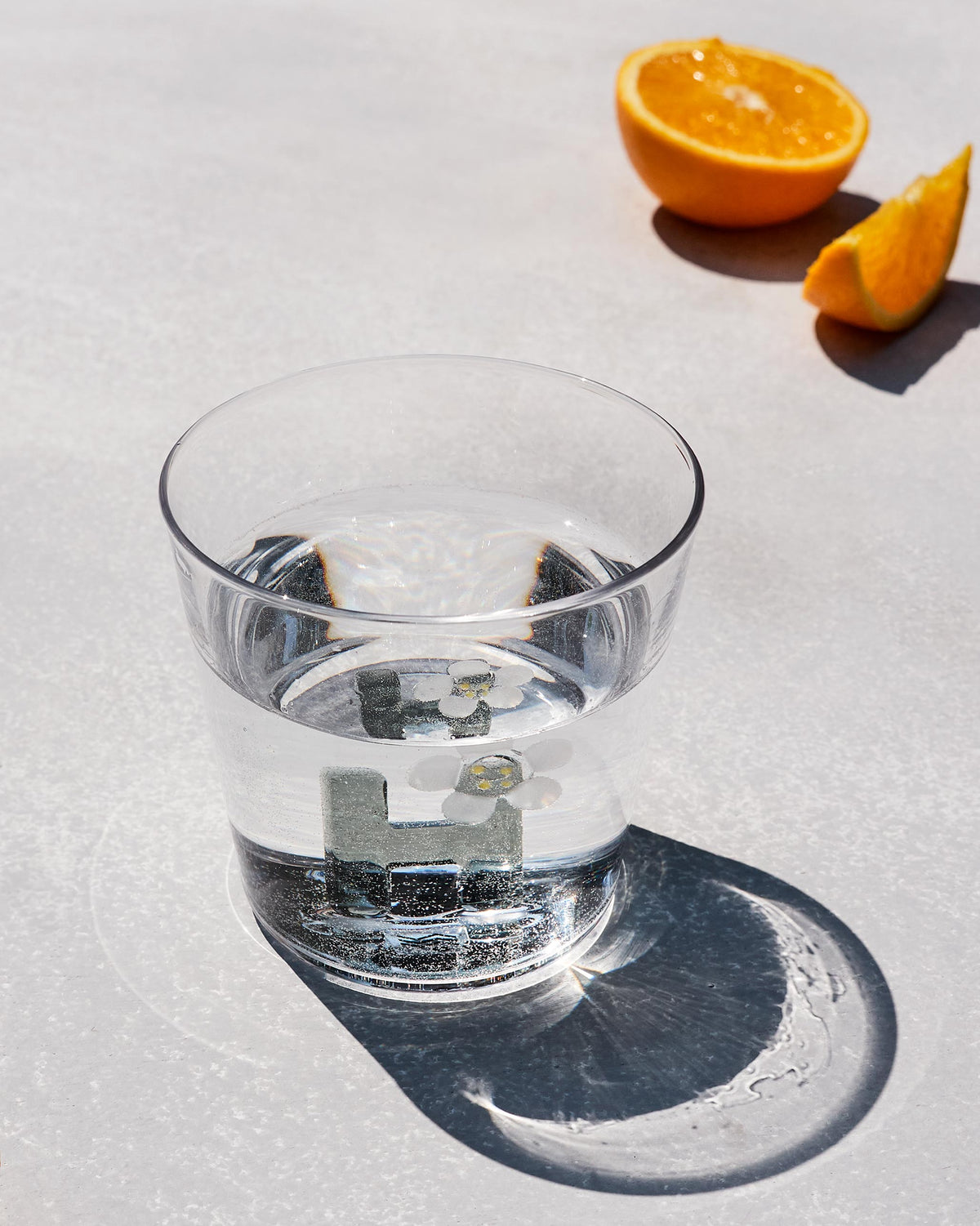 Clear Alphabet glass with a 3D letter H and white flower, filled with water.