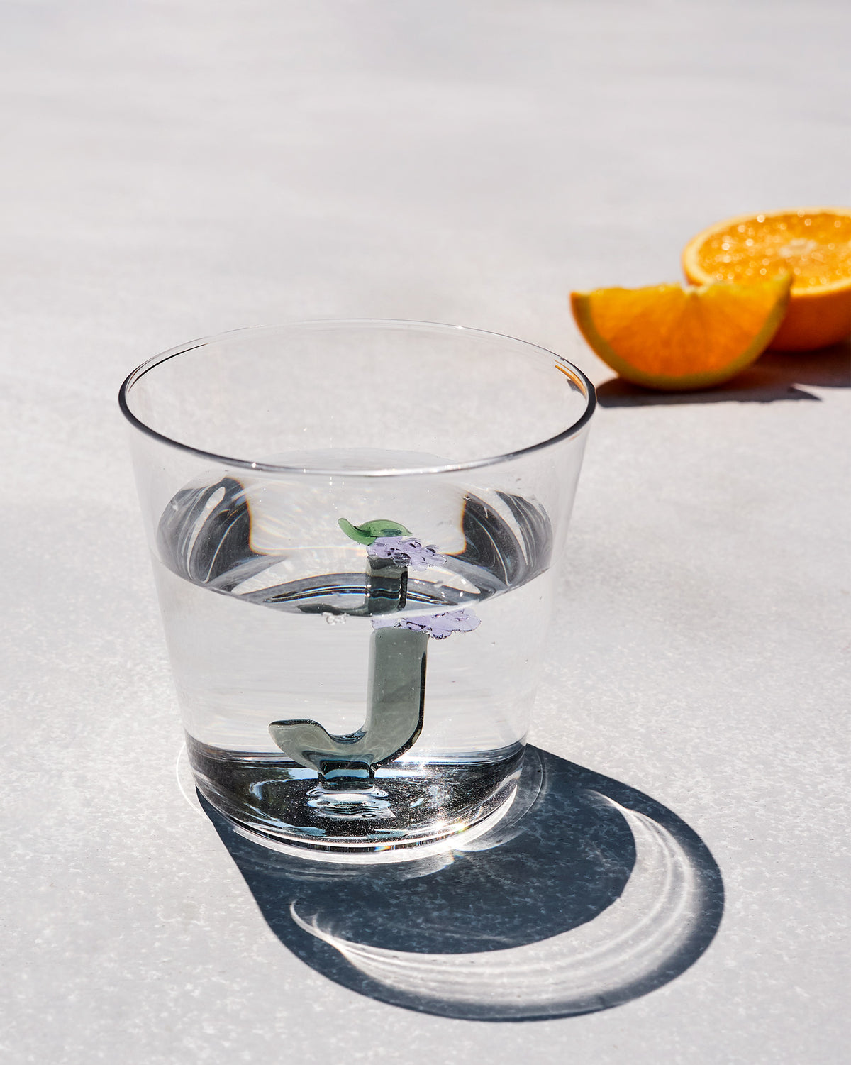 Clear Alphabet glass with a 3D letter J and purple flowers, filled with water.