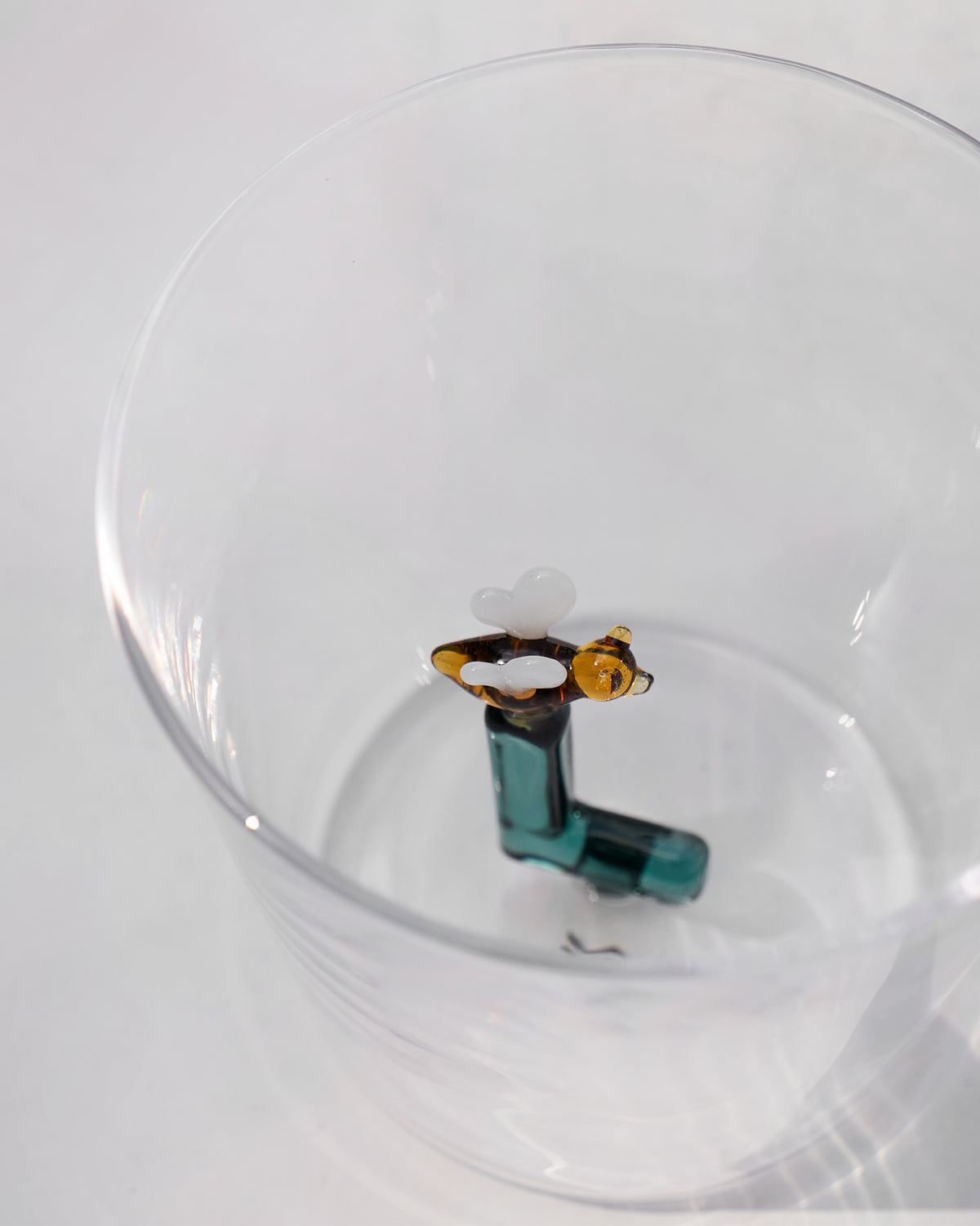 Overhead view of an Alphabet glass with a teal letter L and amber butterfly.