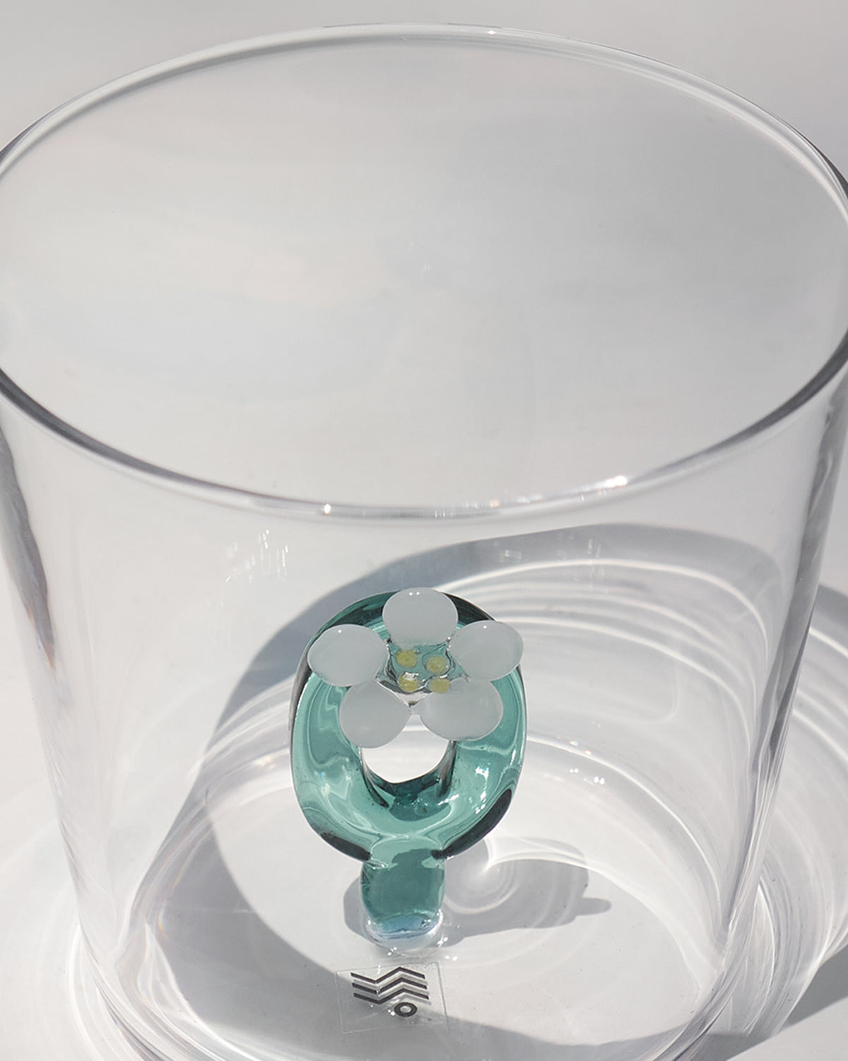 Overhead view of an Alphabet glass with a teal floral letter O.