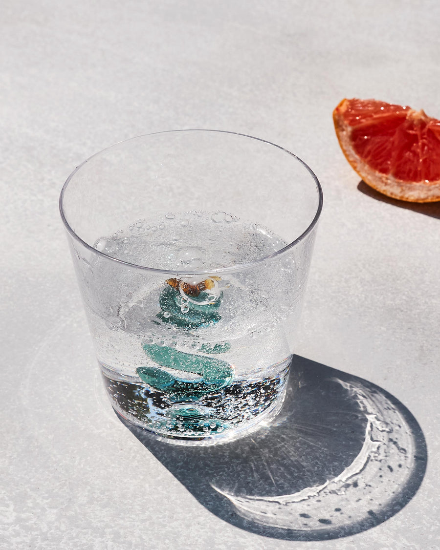 The S glass with sparkling water beside a slice of grapefruit