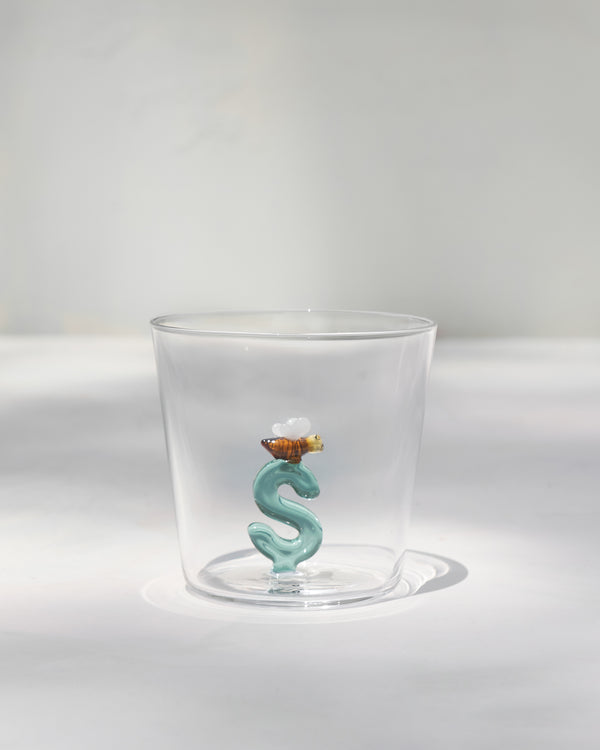 The empty glass, a teal S at the base