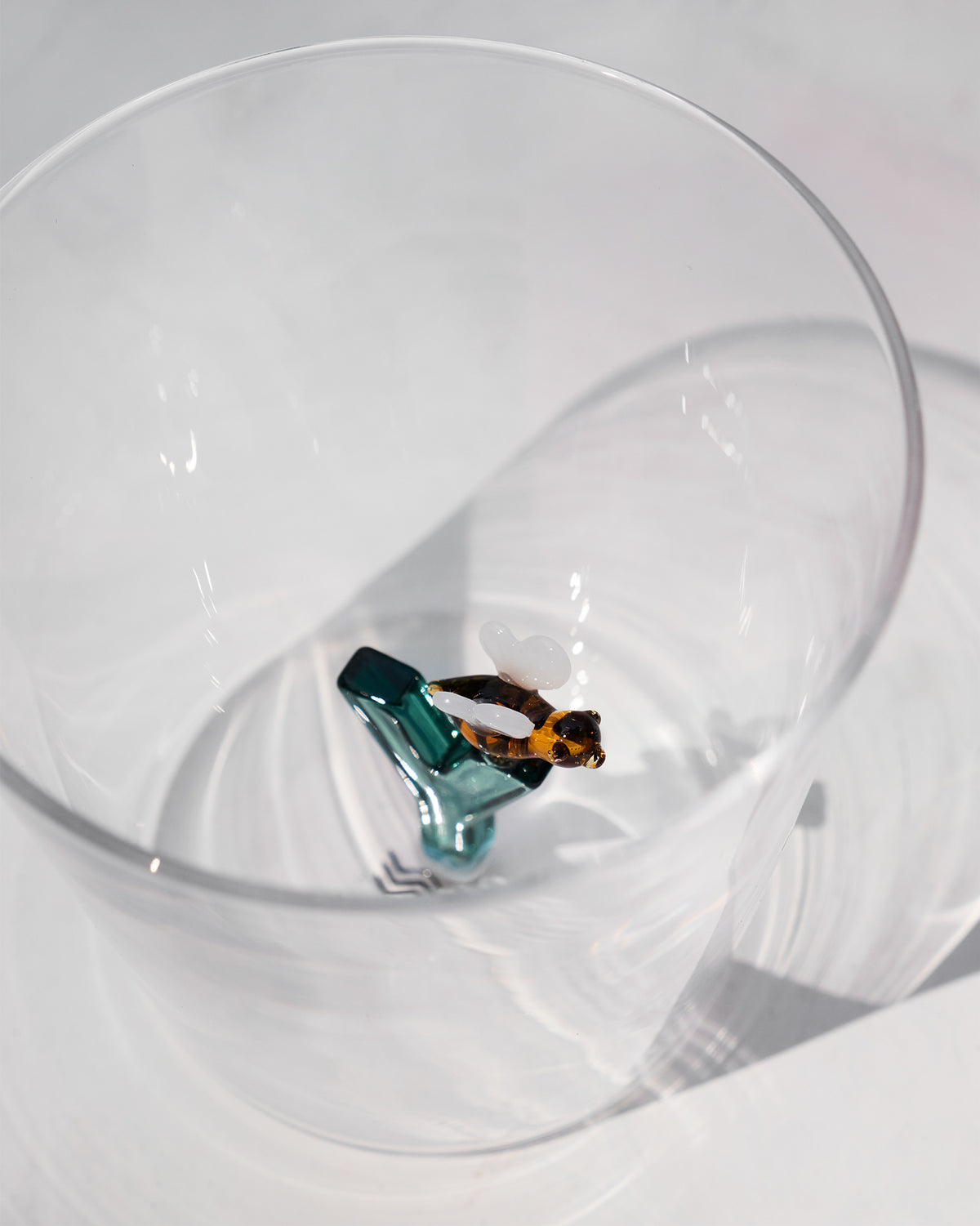 Overhead view of an Alphabet glass with a teal letter Y and amber bee.