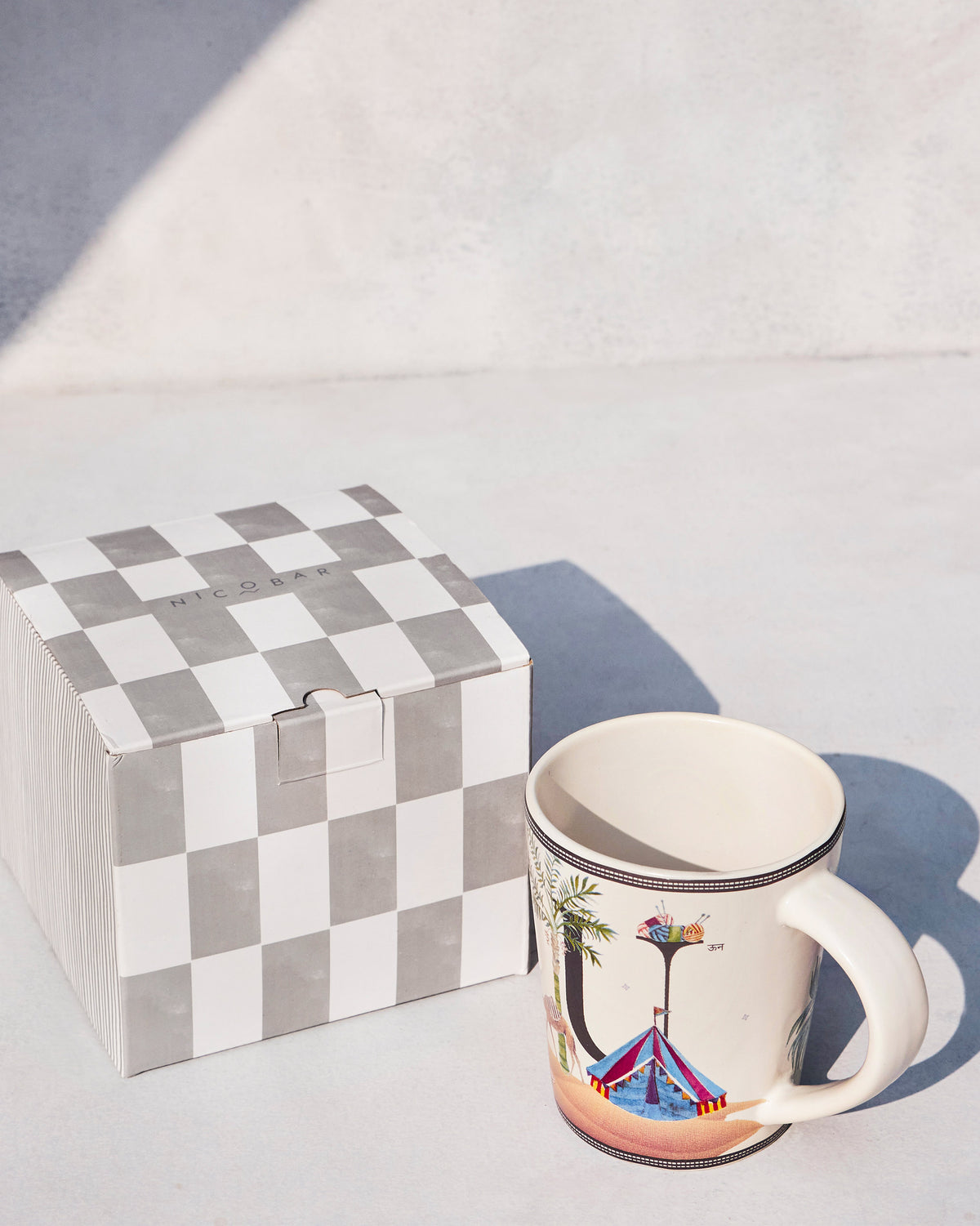 Cream Umbrella alphabet mug beside a grey-and-white checked Nicobar gift box.