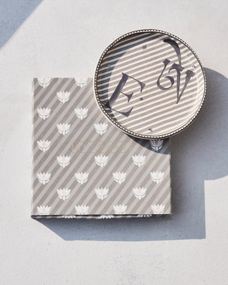 The Akshar Coaster beside its striped gift box.