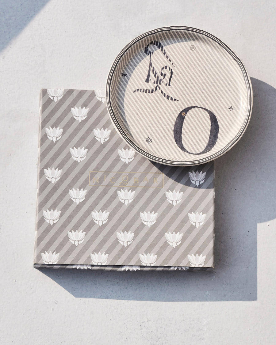 The Akshar Coaster beside its striped gift box.