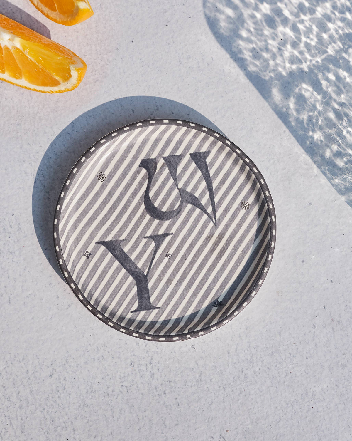 Akshar Coaster - Y laid flat, showing the grey Y glyph on diagonal stripes.