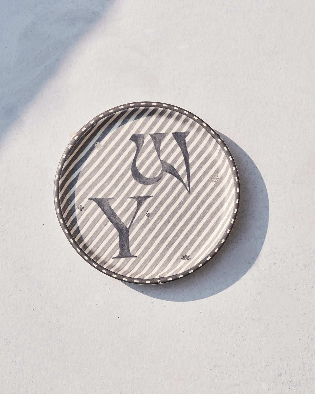 Akshar Coaster - Y lying flat, showing its beaded rim and grey Y glyph.