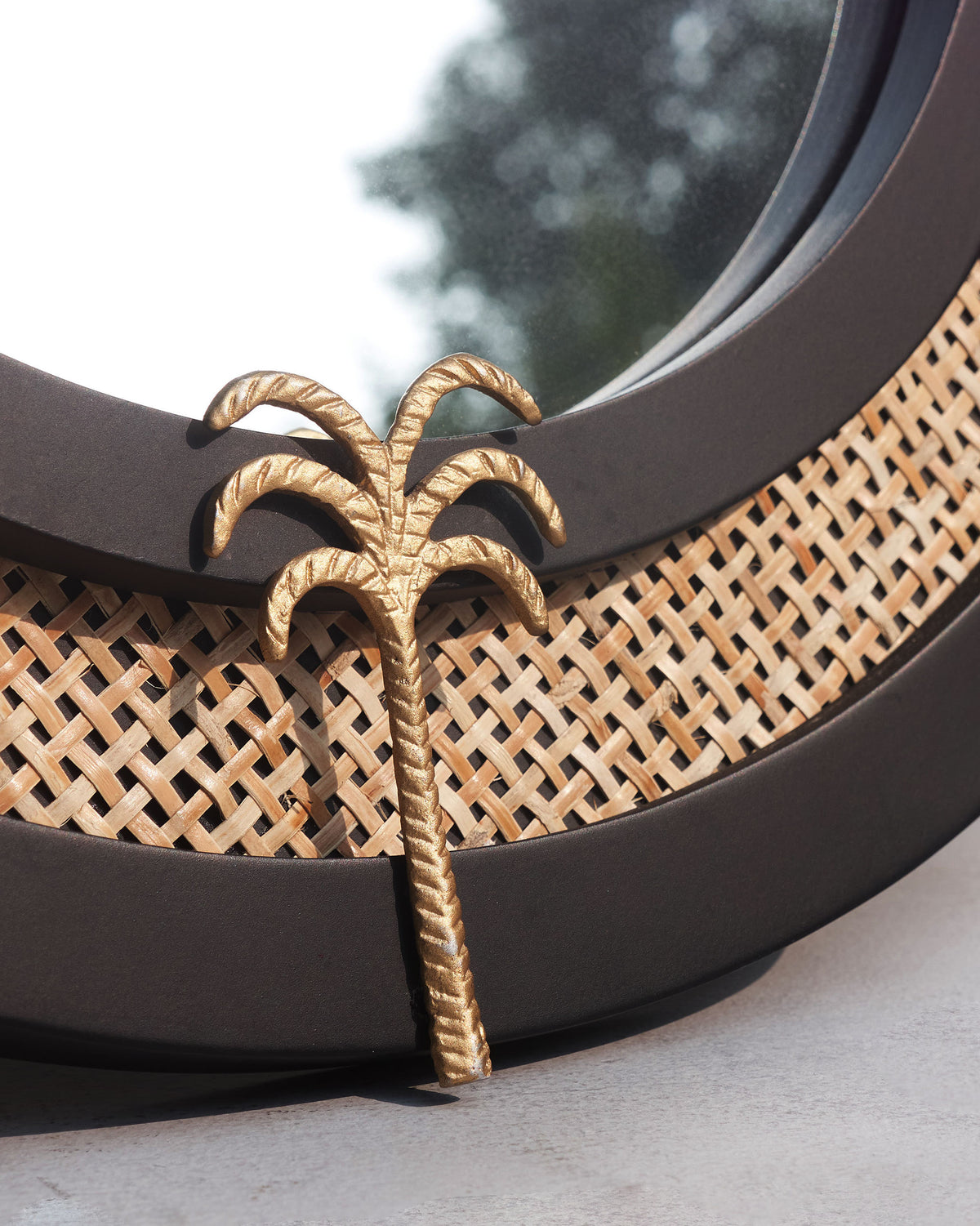 Close-up of a Suesgad Mirror showing its gold palm detail and woven cane ring.