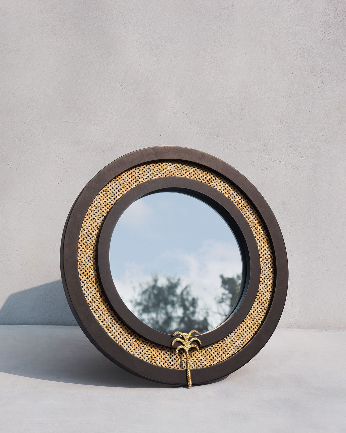 Suesgad Mirror with a dark frame and a gold palm detail at its base.