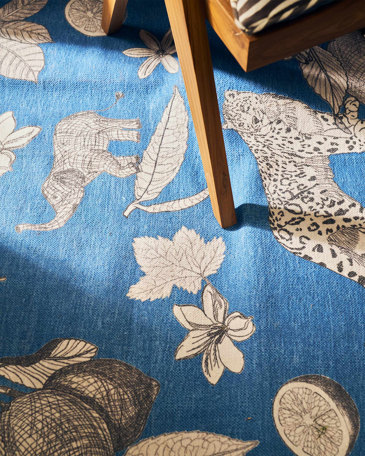 Close-up of Forest Rug in navy showing a leopard, elephant and leaf motifs.