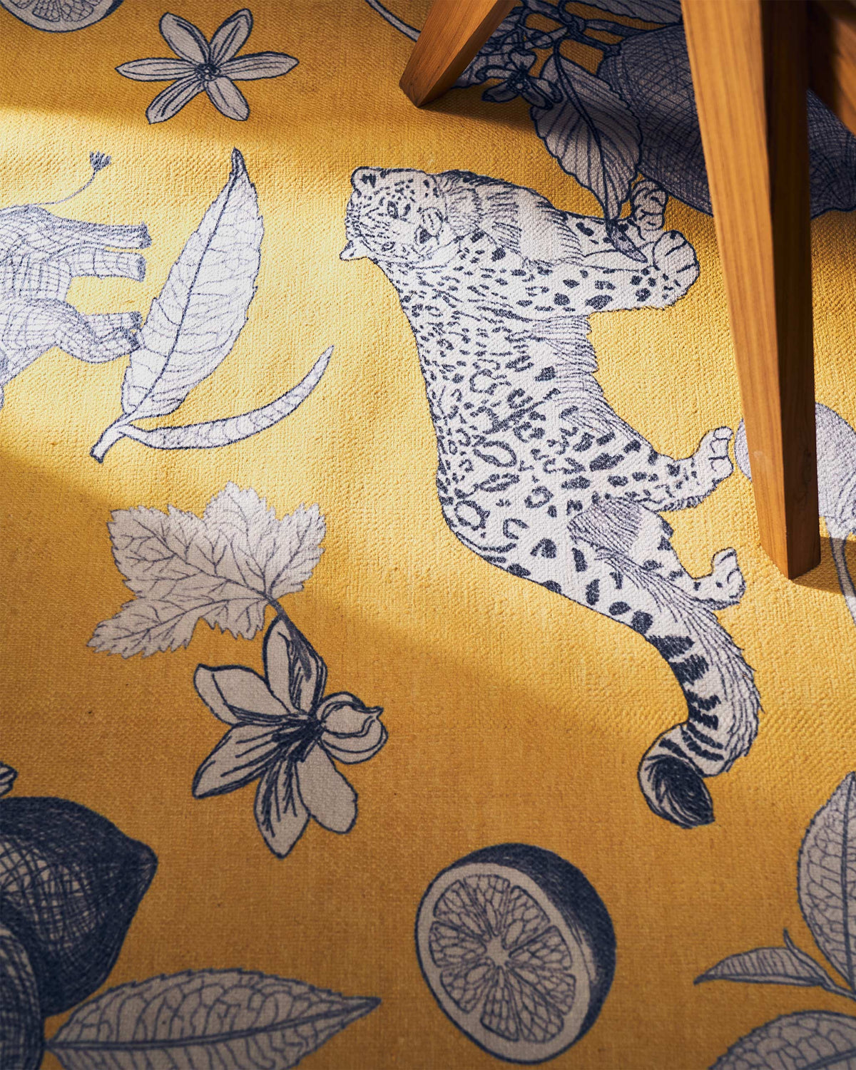 Close-up of Forest Rug in yellow showing a navy leopard and leaf motifs.