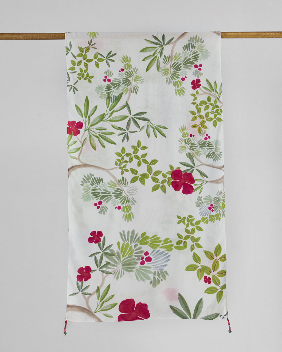 Full Alaya scarf in white with green foliage and red flowers, hung from a rod.
