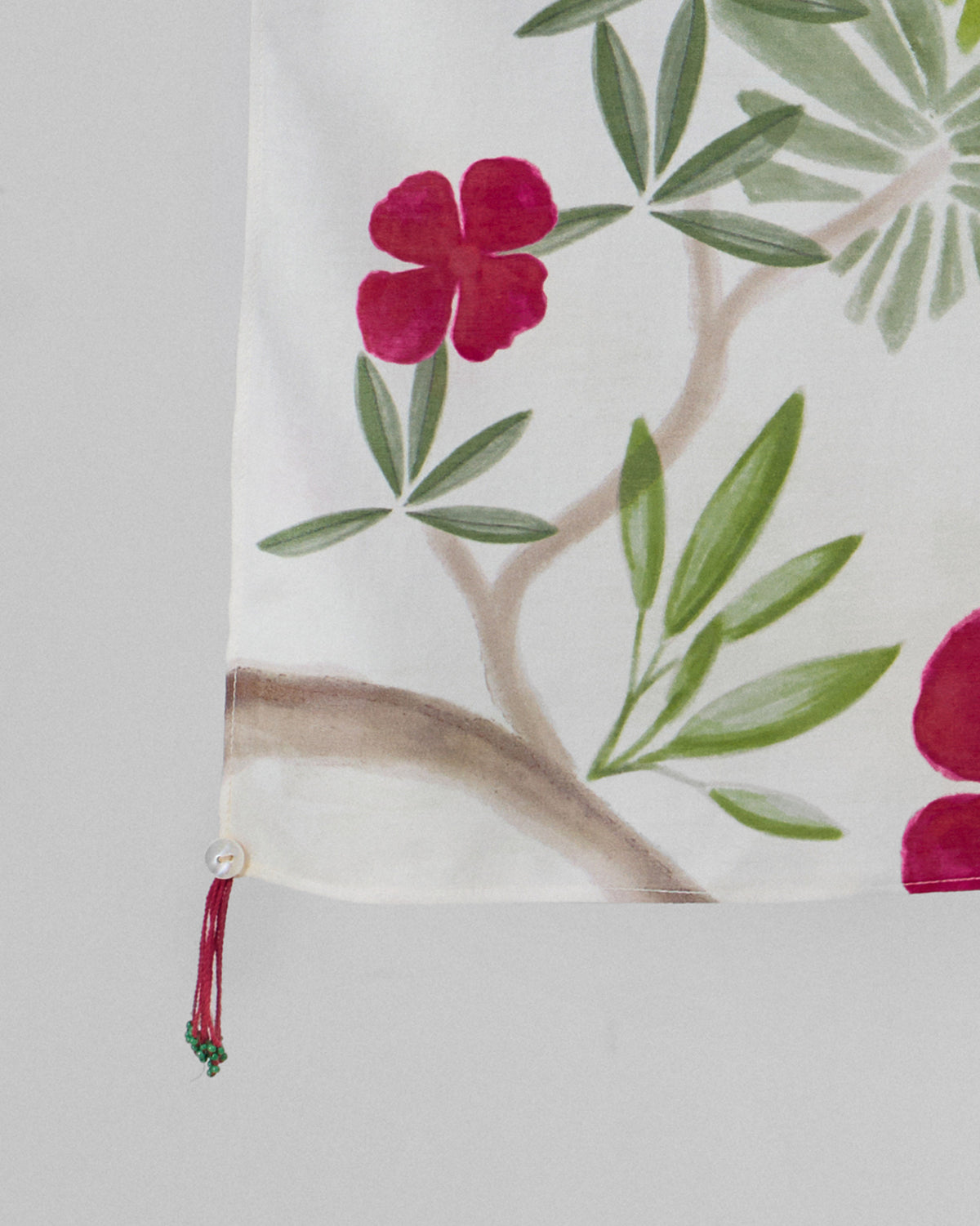 Close-up of the Alaya scarf corner showing a red flower and a small red tassel.