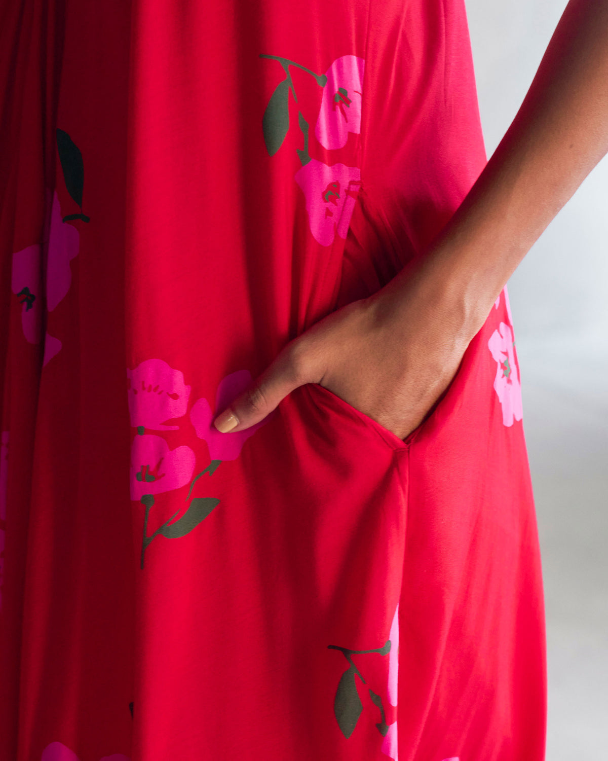 Close-up of a hand in the side pocket of the red Akira Twist Back Dress.