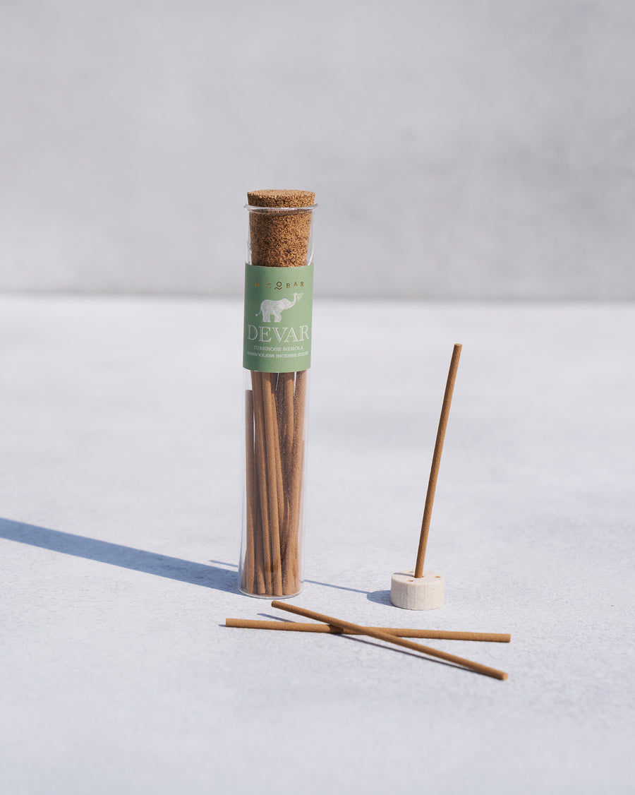 An incense stick in a holder beside the tube.