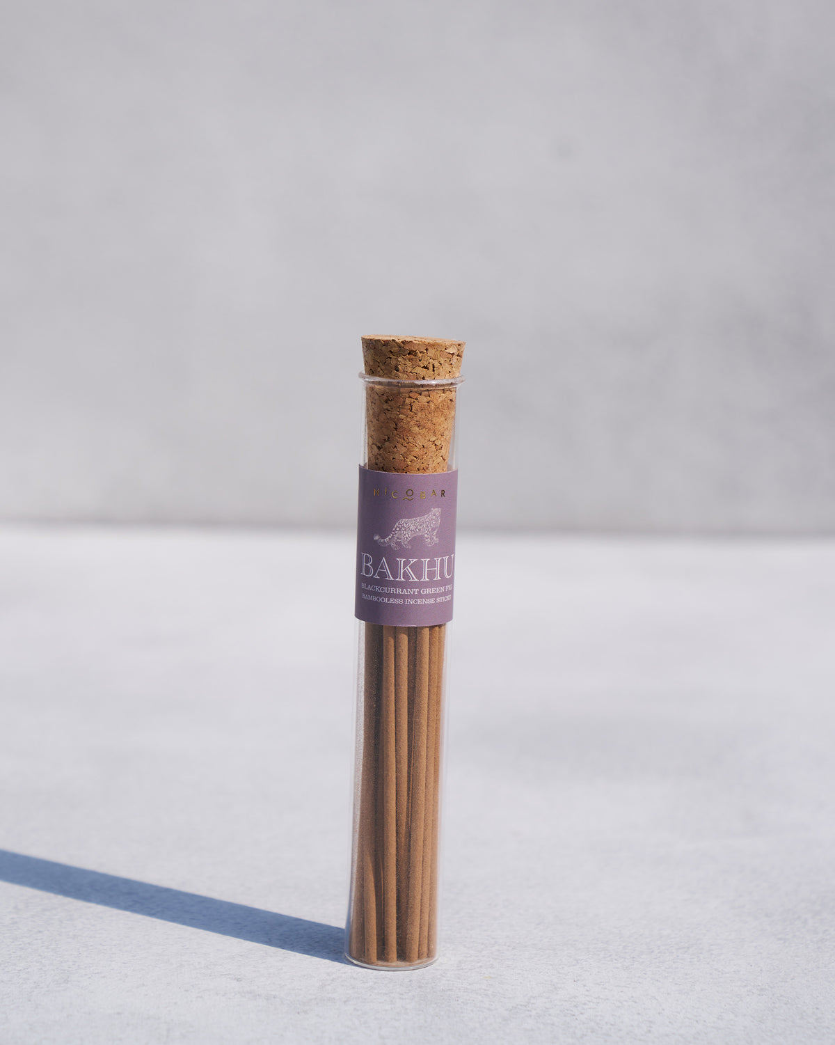 Bakhu incense sticks in a clear tube with a cork stopper and purple label.