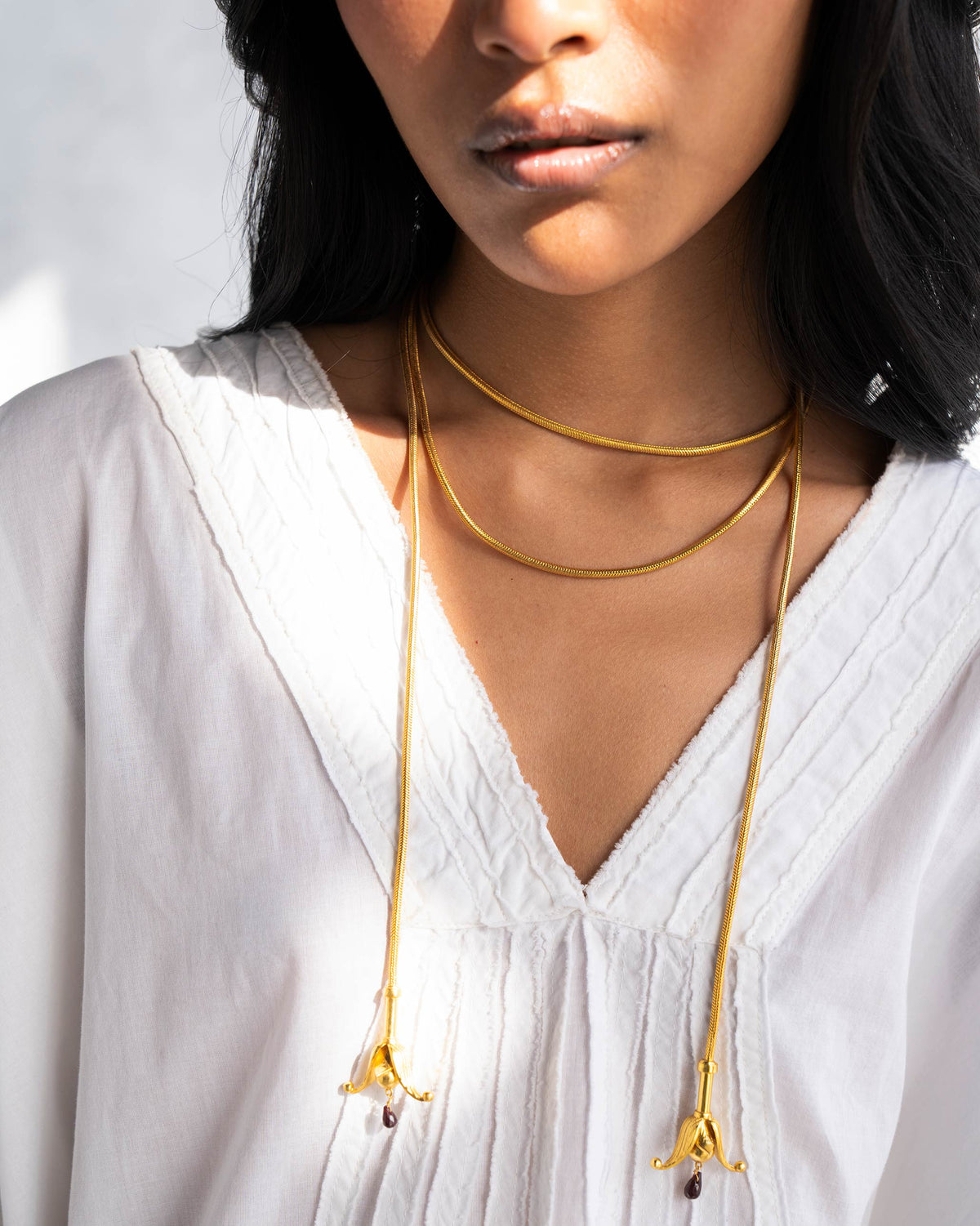 Person wearing gold Phool Chains with flower-shaped ends.