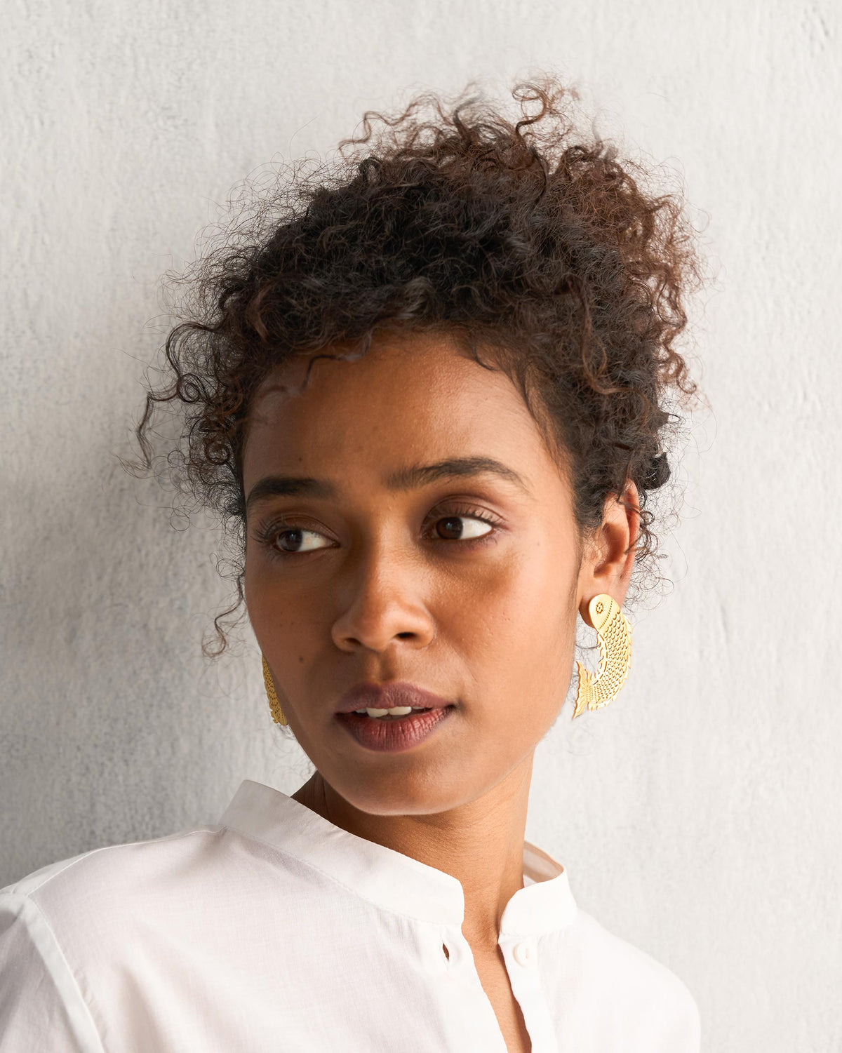 Person wearing gold Meen Earrings.