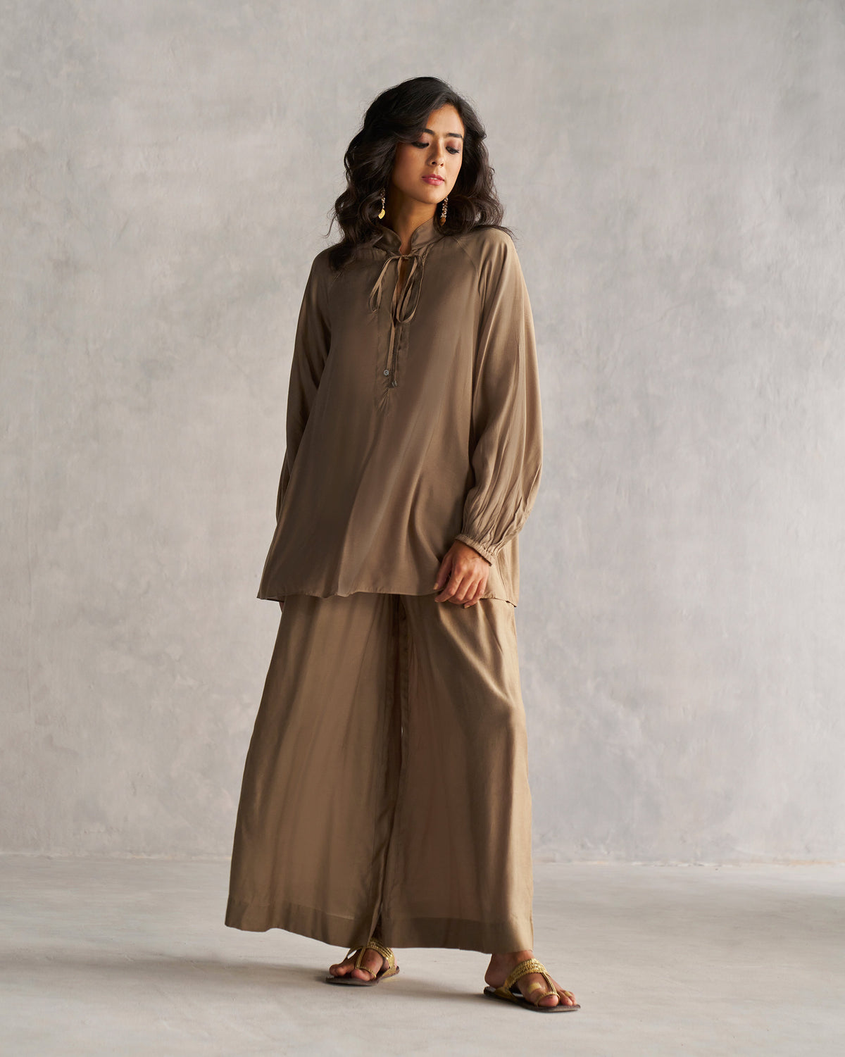 Person wearing a long oak brown raglan blouse.