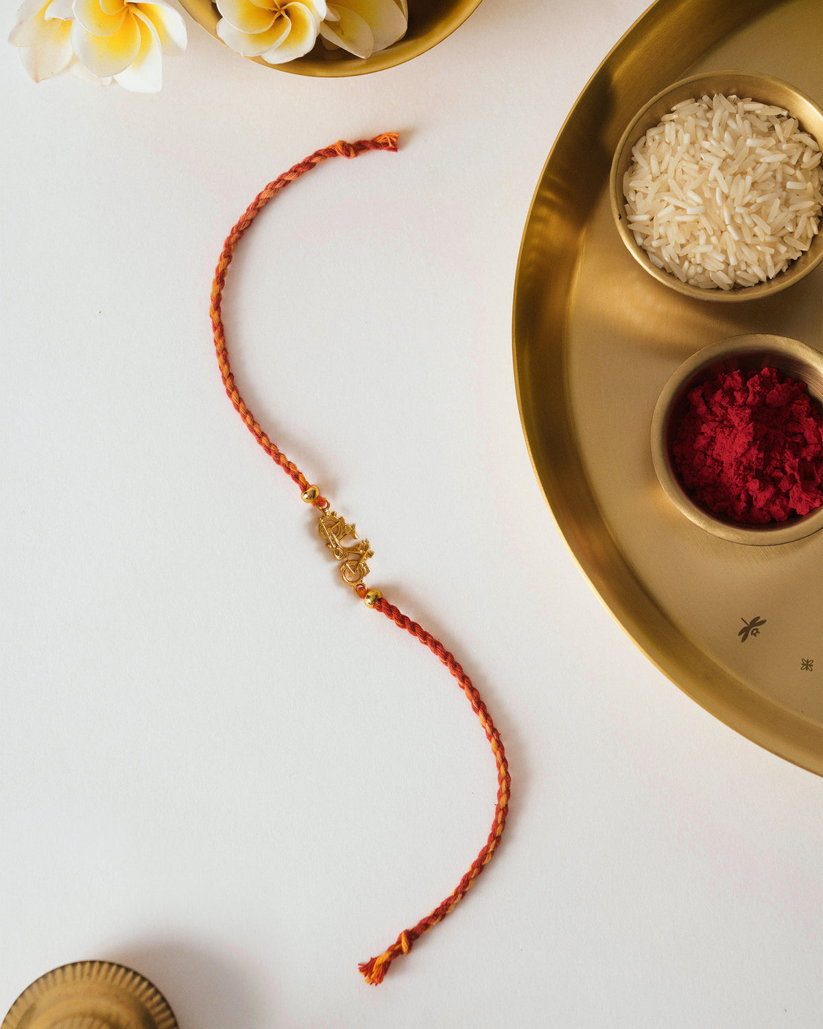 Motor Cycle Rakhi with a red braided thread and gold charm, laid flat.