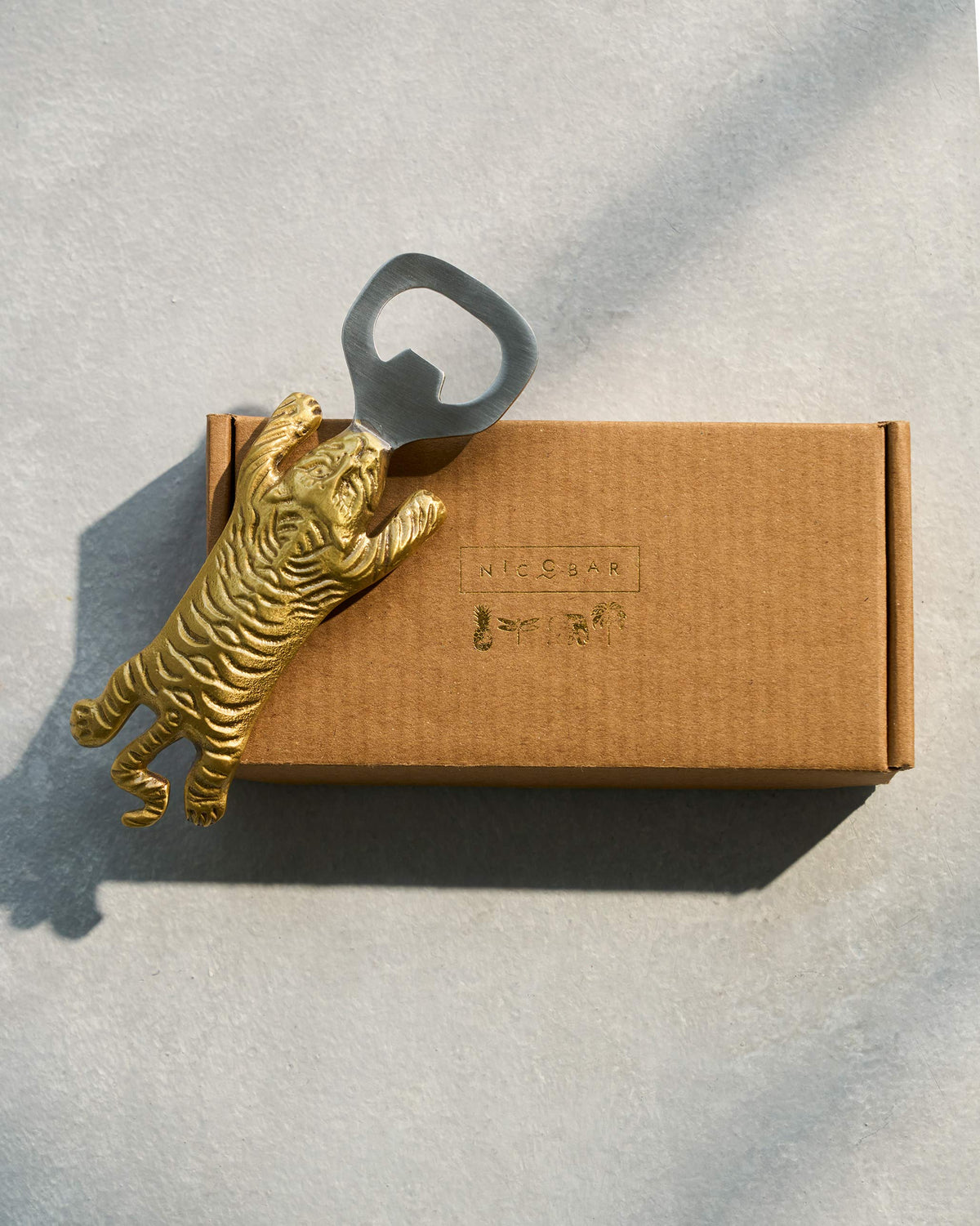 Gold Sumatran tiger bottle opener on a Nicobar gift box.