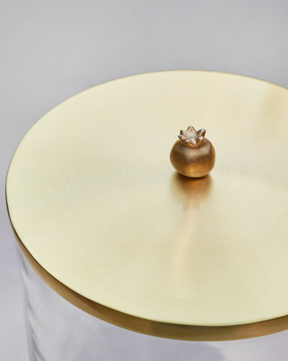 Close-up of the gold Mistle dispenser lid with a pomegranate knob.