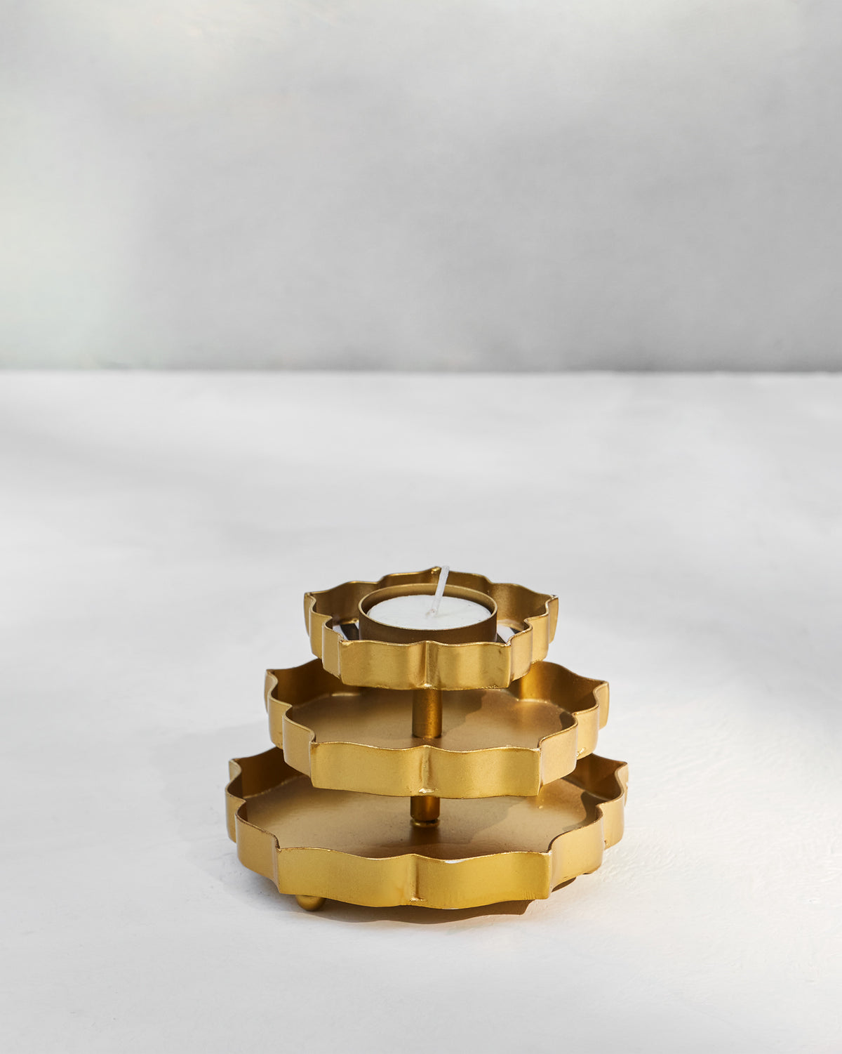 Three-tier gold Sama votive with scalloped trays and a tealight.