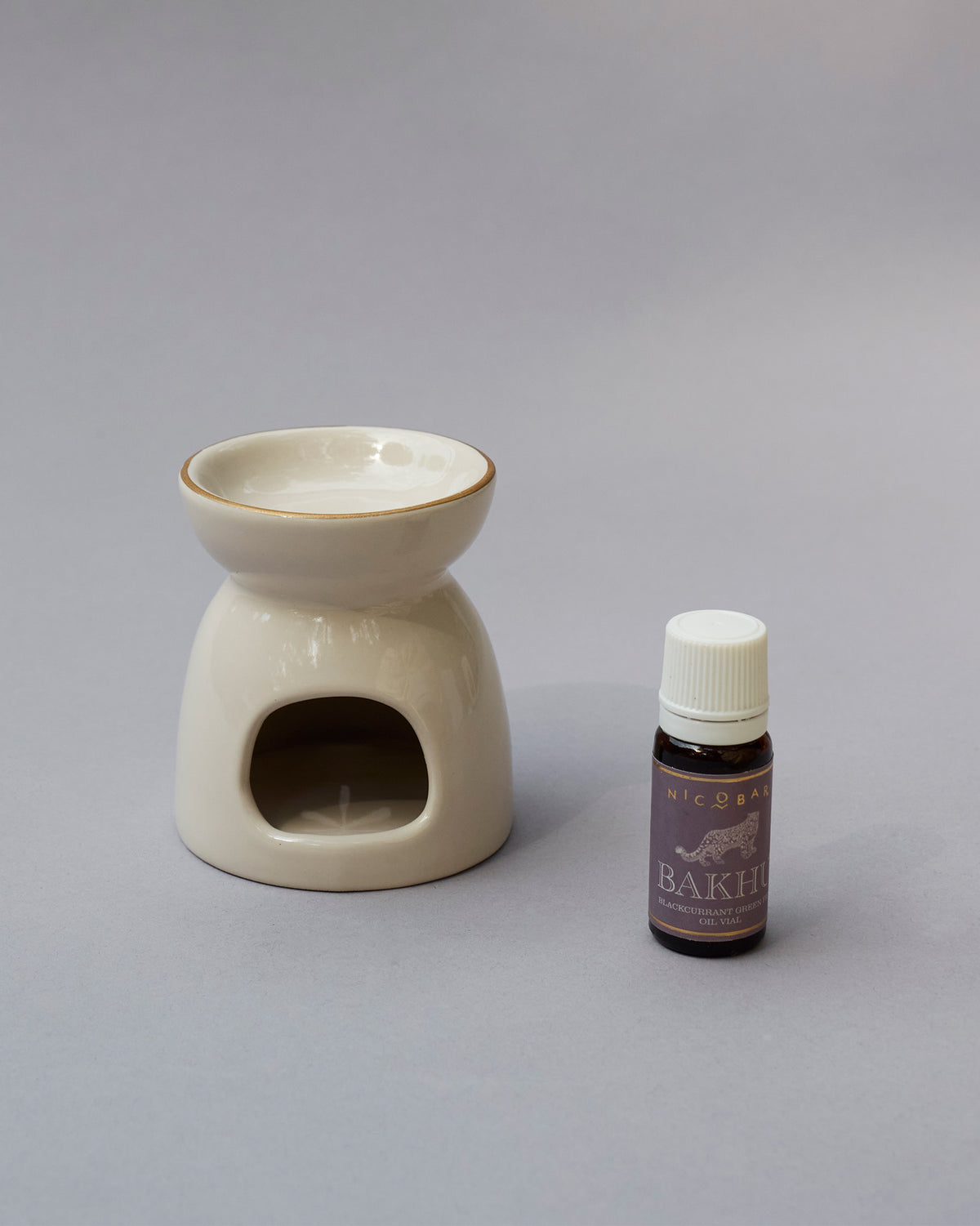 Cream ceramic oil burner beside a small bottle of oil.