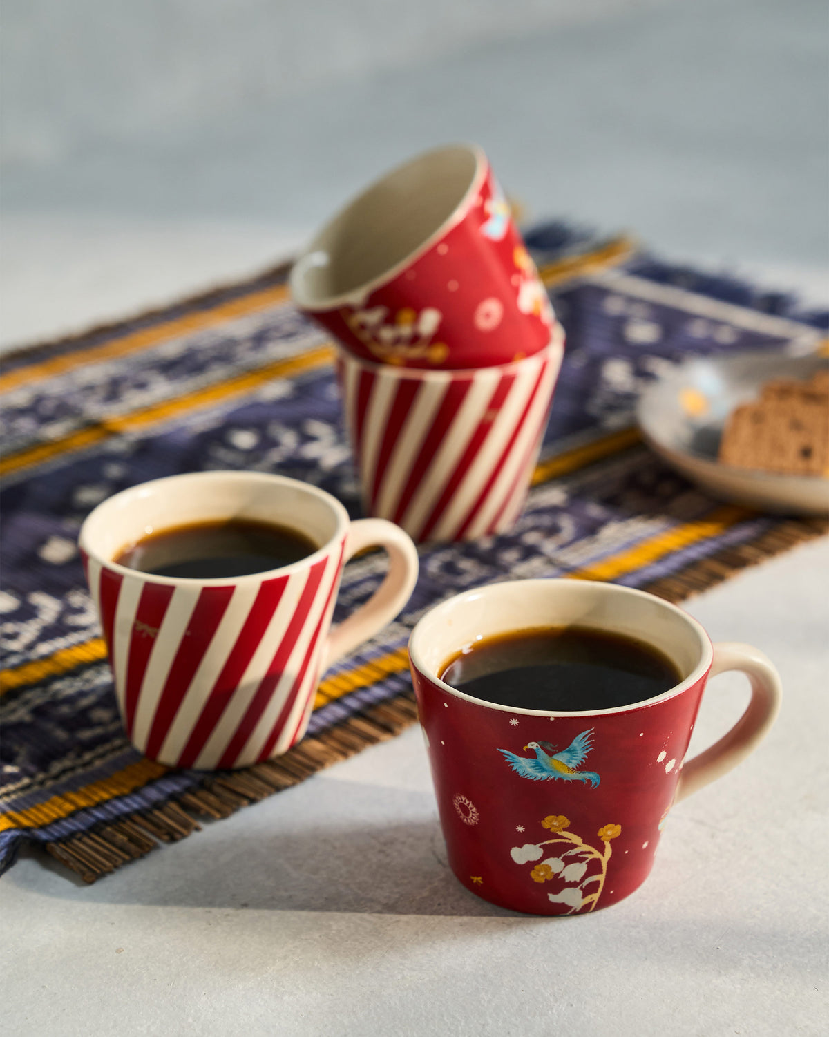 Phoenix espresso mugs with coffee, showing red stripes and bird print.