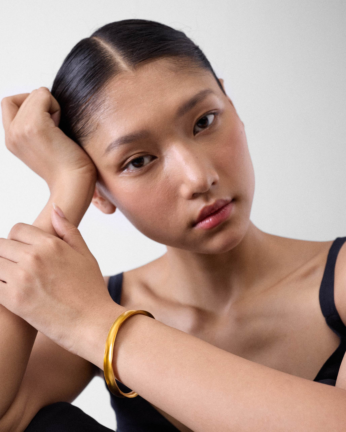 Person wearing a thin gold Batur wavy cuff bangle on the wrist.
