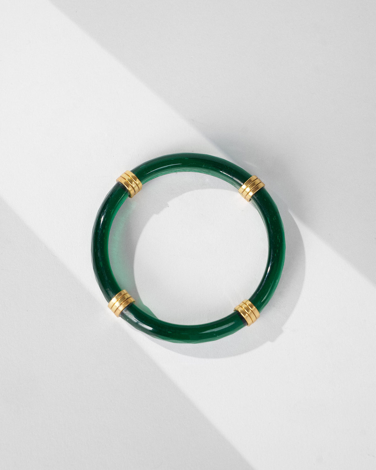 Glossy green Cara glass bangle with gold metal accents.
