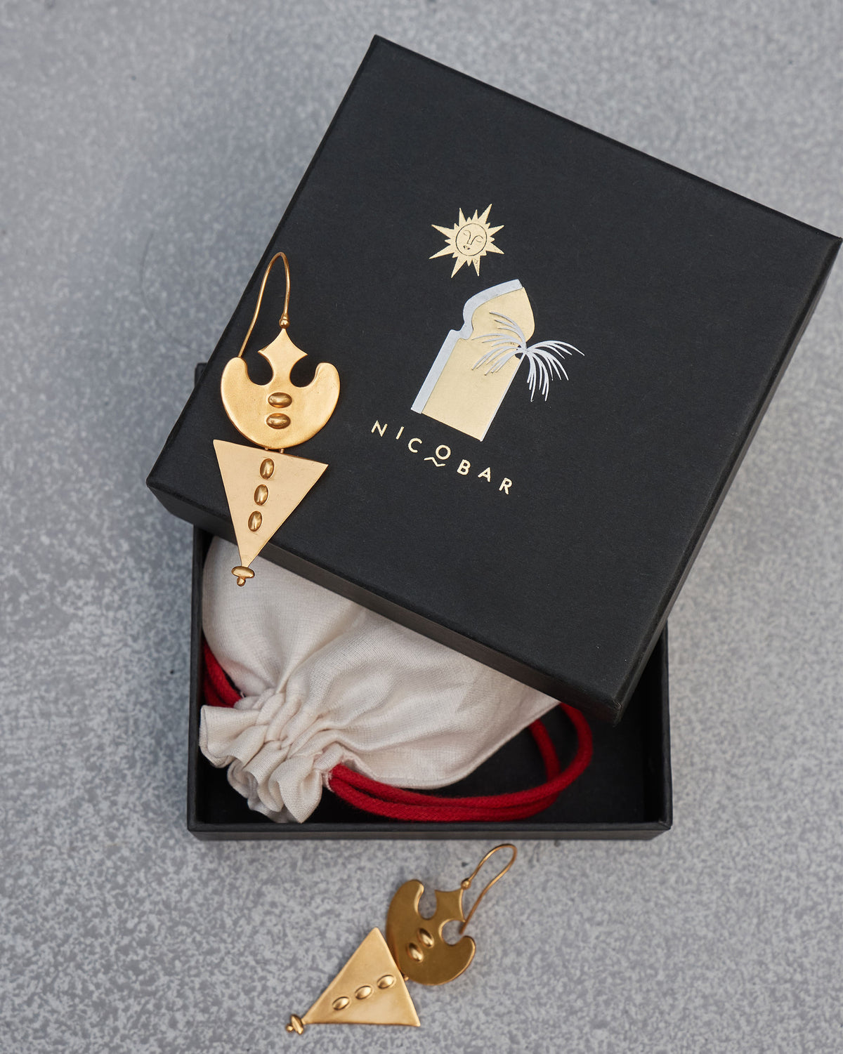 Gold Lama Earrings in a black gift box beside a cream pouch.