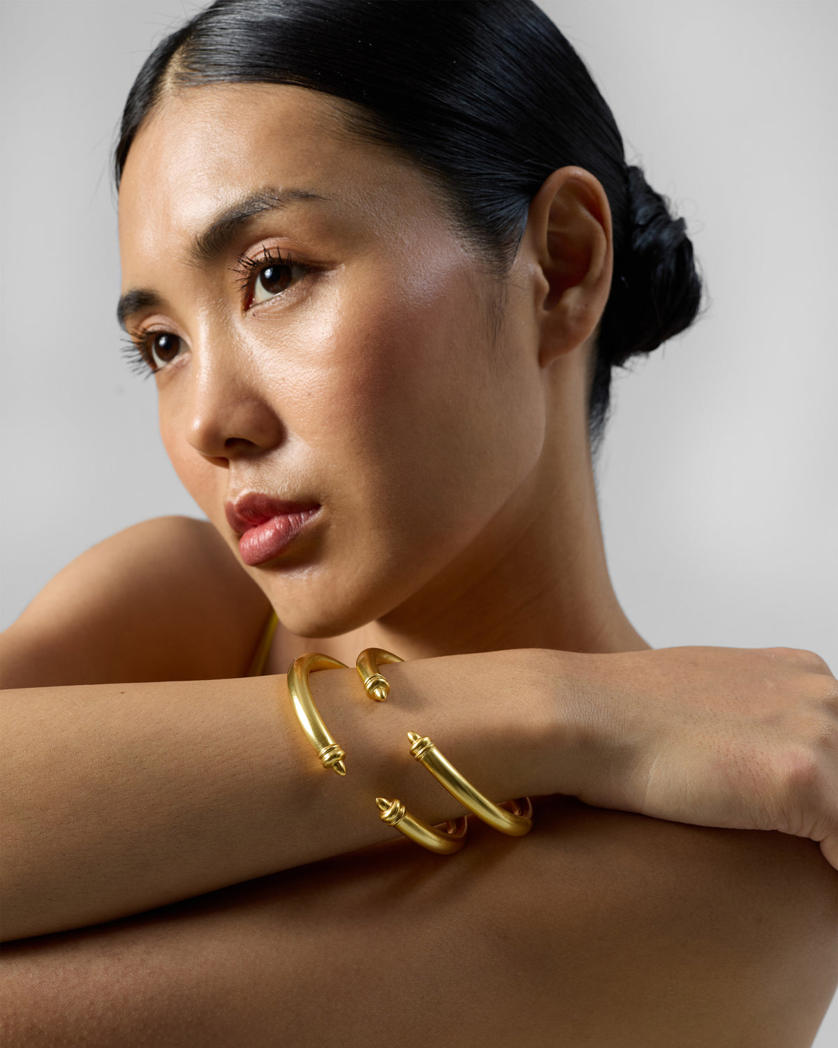 Person wearing stacked gold Raahi open cuff bangles.