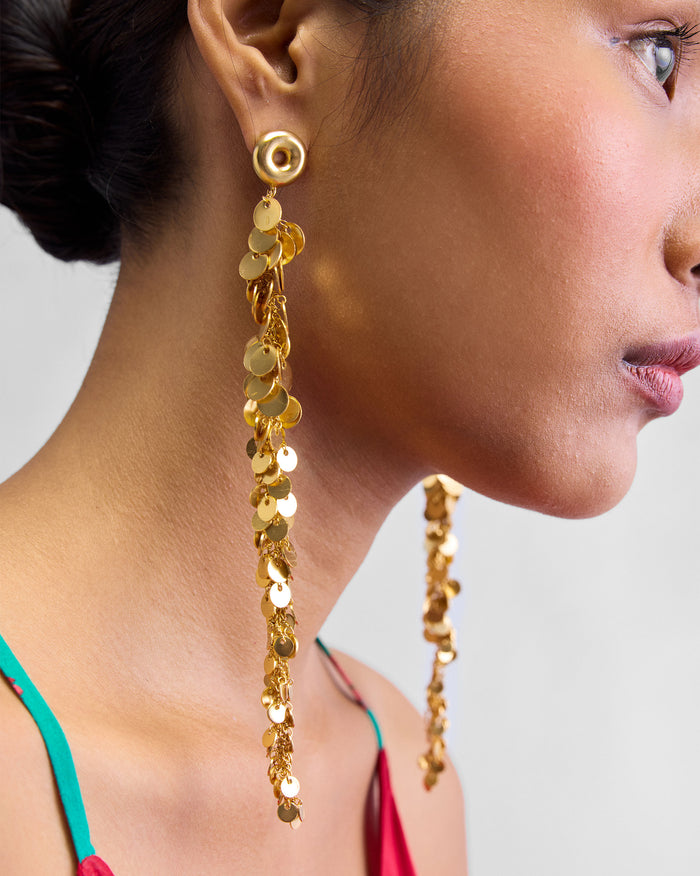 Person wearing a long gold Tassel Shoulder Duster with disc-shaped charms.