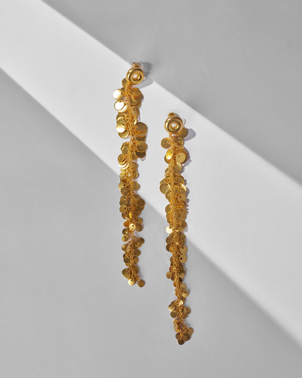 Pair of long gold Tassel Shoulder Dusters with disc-shaped charms, laid flat.
