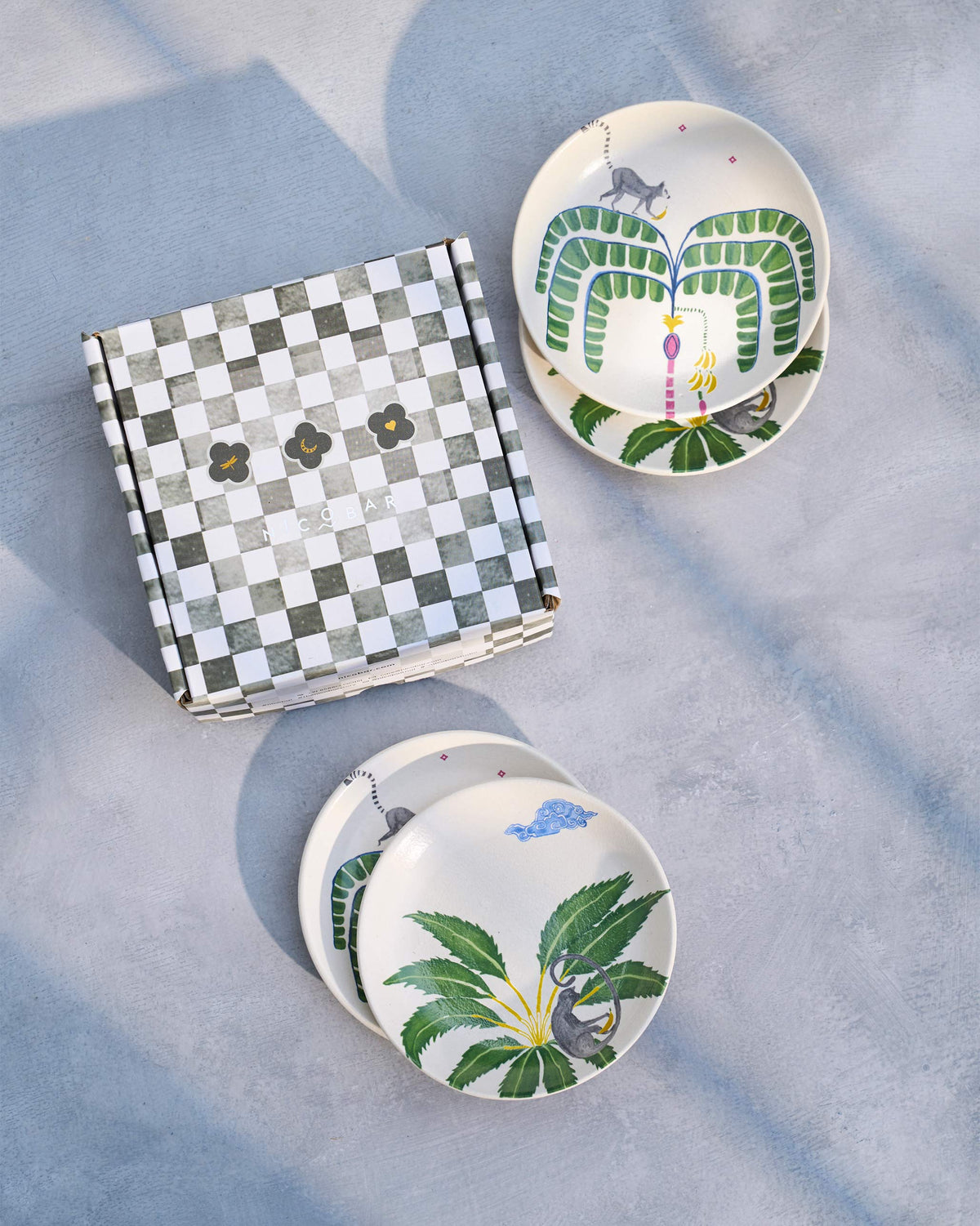 Safari tea plates stacked beside their checkered gift box.
