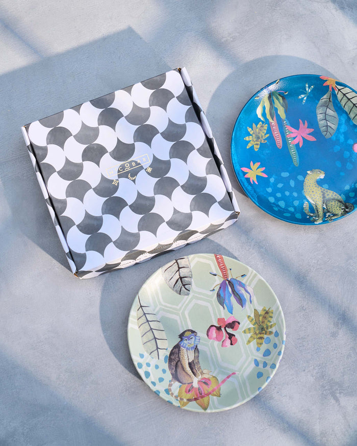 Pair of Mahi quarter plates with monkey and leopard prints beside gift box.