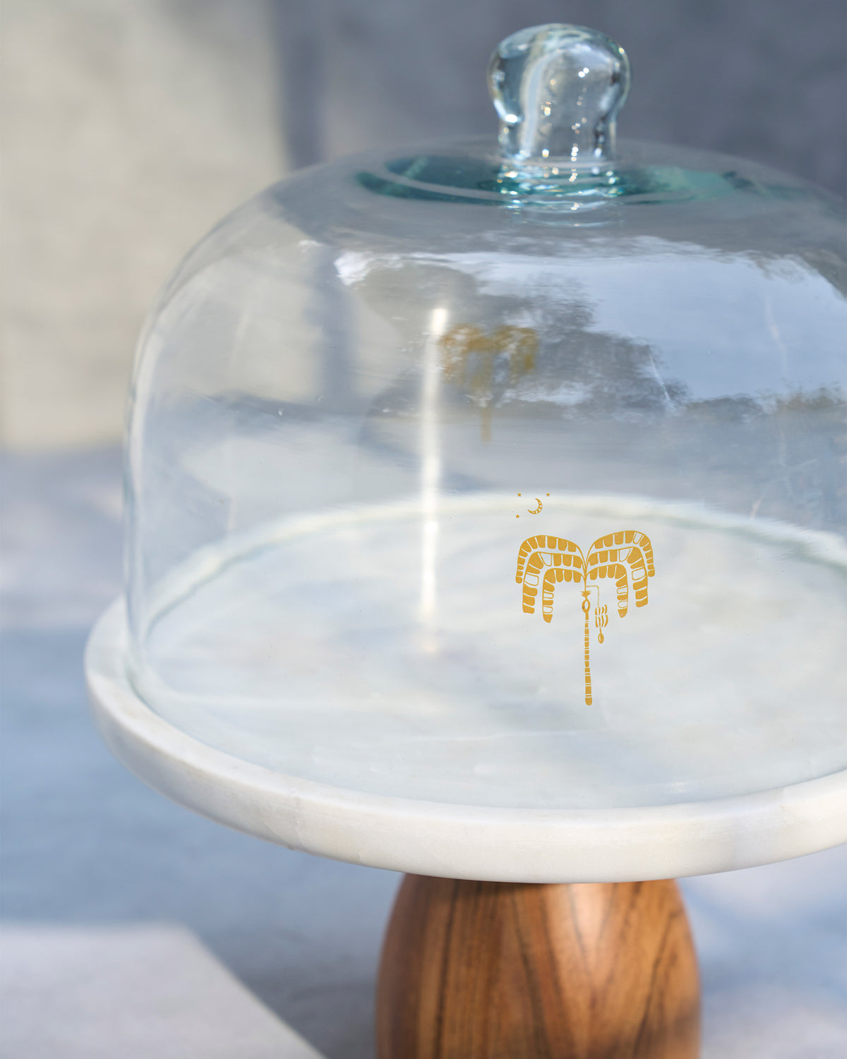 Close-up of the Safari Cloche dome with a small gold motif on the glass.