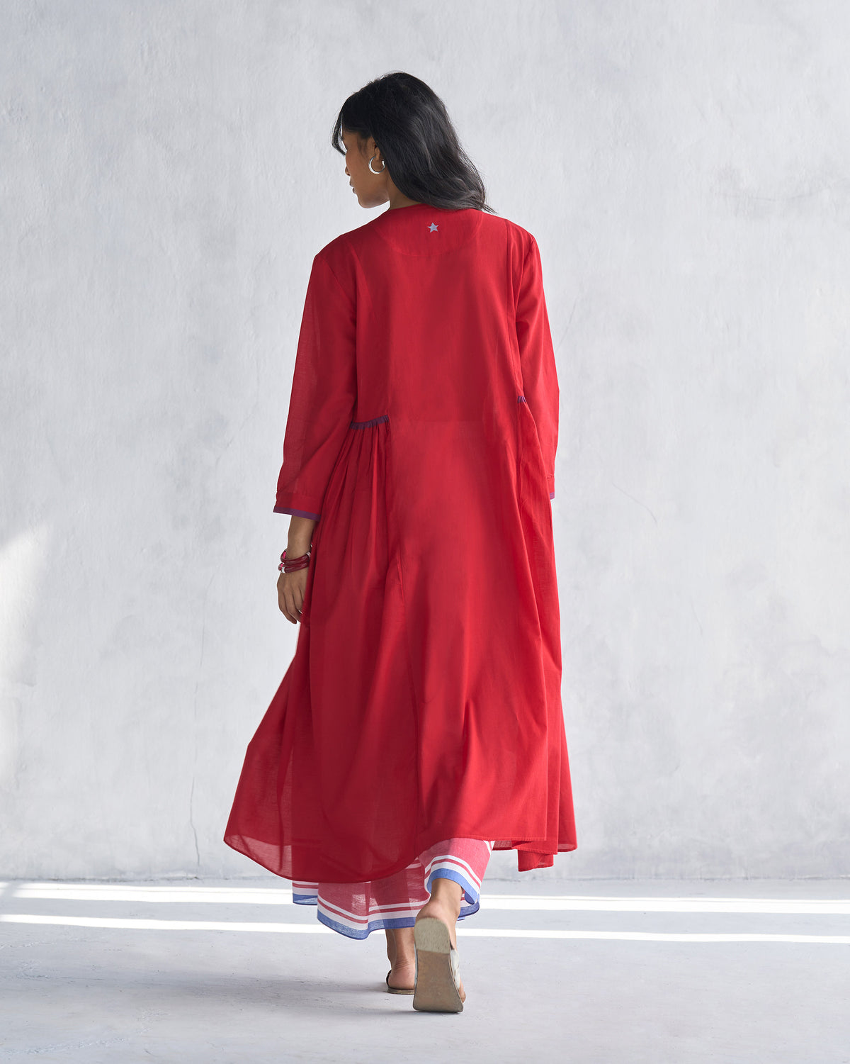 Back of a red Pintuck kurta showing the flared A-line length and blue cuff trim.