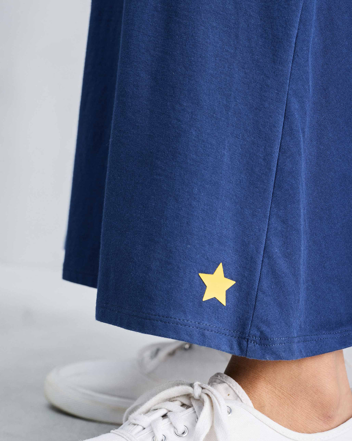 Close-up of a yellow star near the hem of a navy Esther dress.