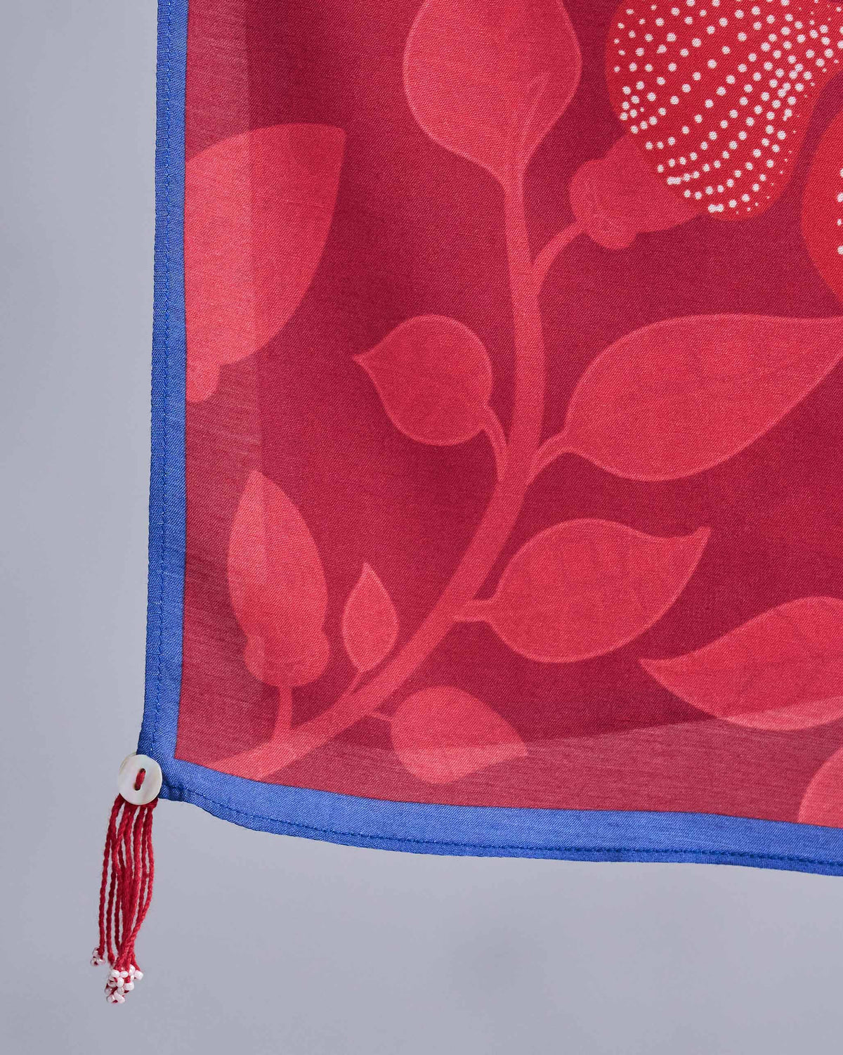 Close-up of red Roseate scarf corner showing tonal leaves and blue edging.