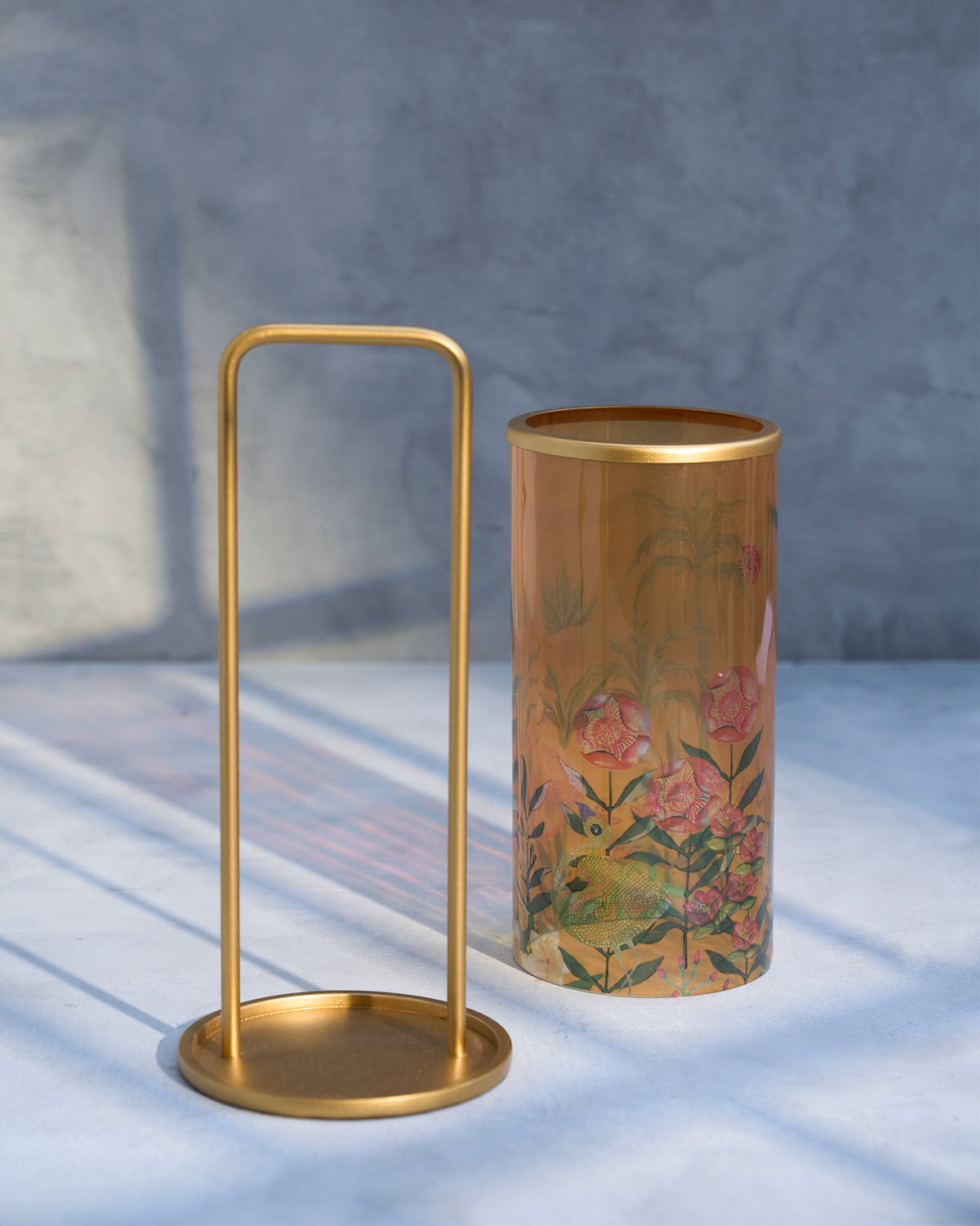 Flamingo Lantern beside its gold stand, showing the printed floral glass.