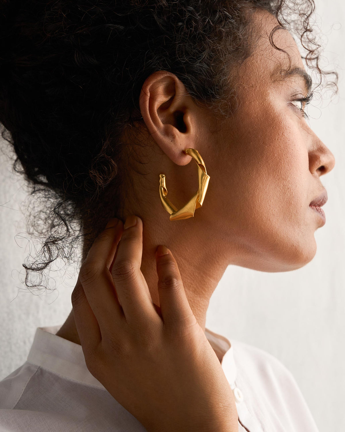 Side profile of Ribbon Hoop Small gold earrings on a person.