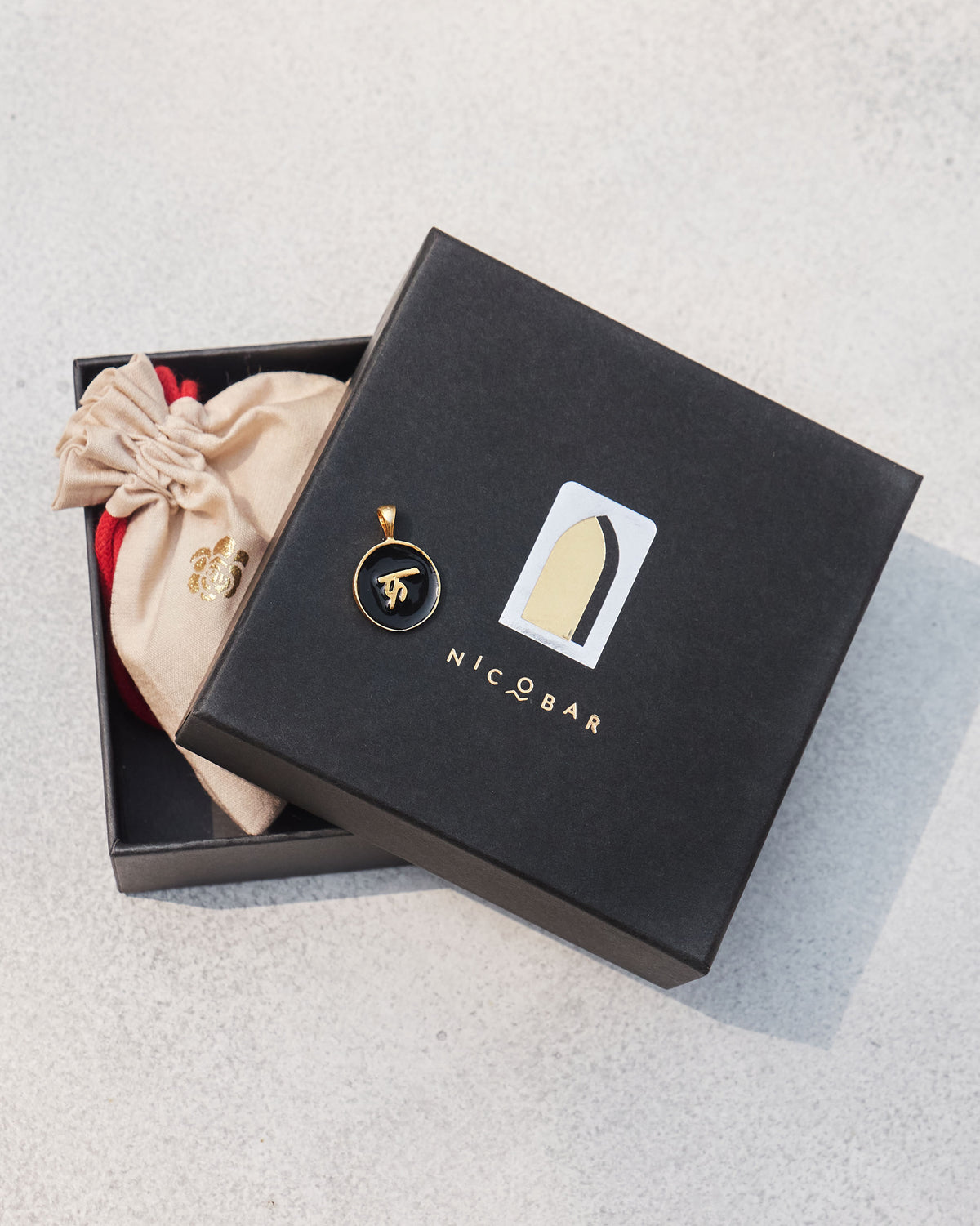 Black and gold alphabet charm on a Nicobar gift box.