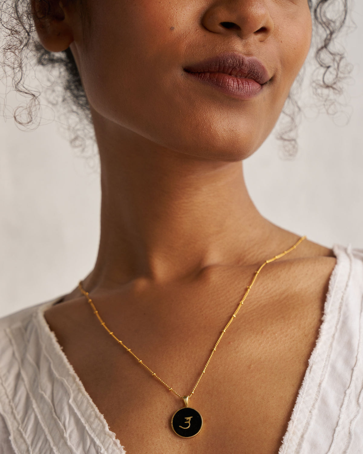 Black and gold Alphabet U charm with a Devanagari letter worn on a satellite chain.